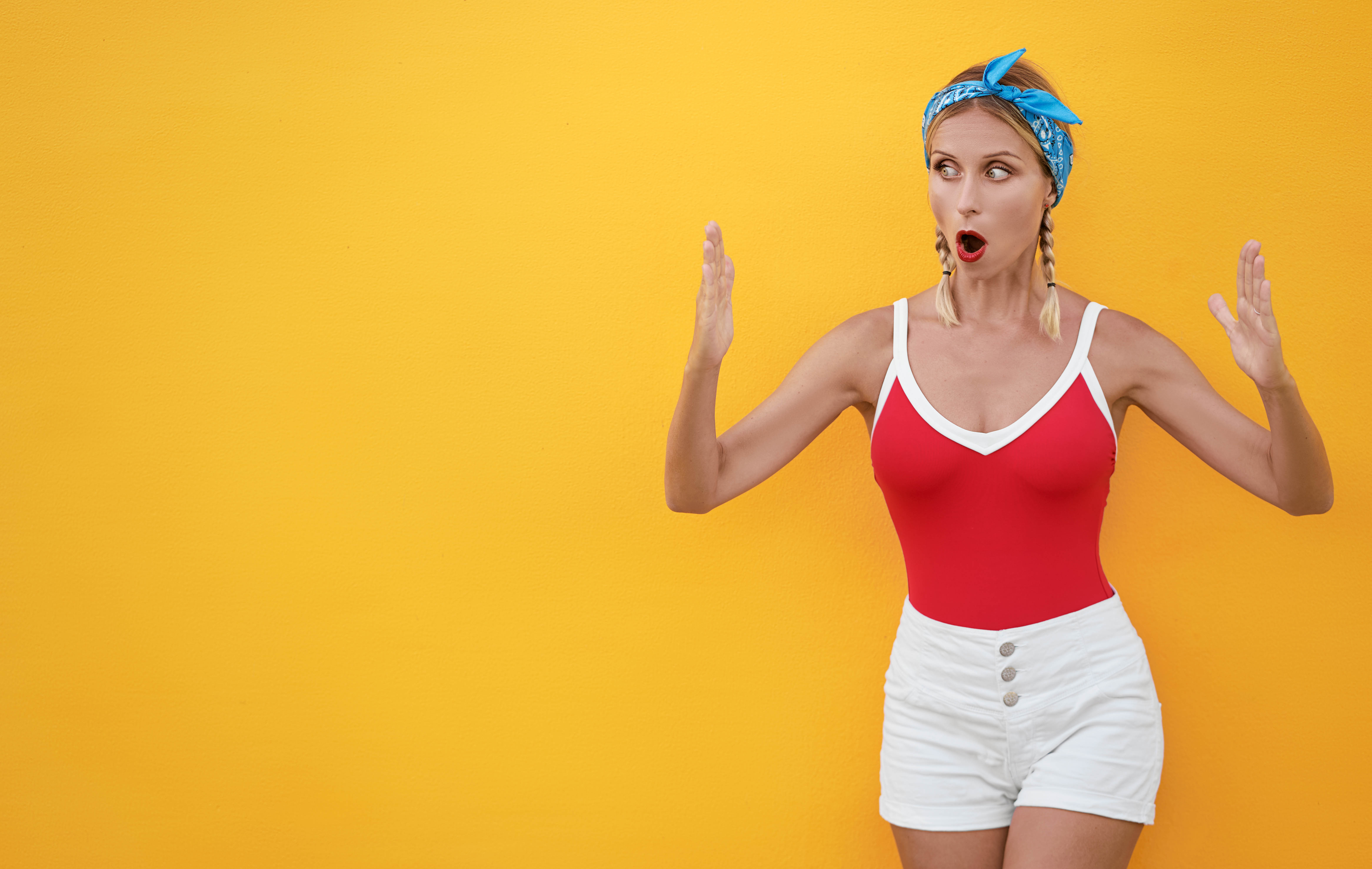 Surprised blonde woman with her hands separated on a yellow background Surprised blonde woman with her hands separated on a yellow background